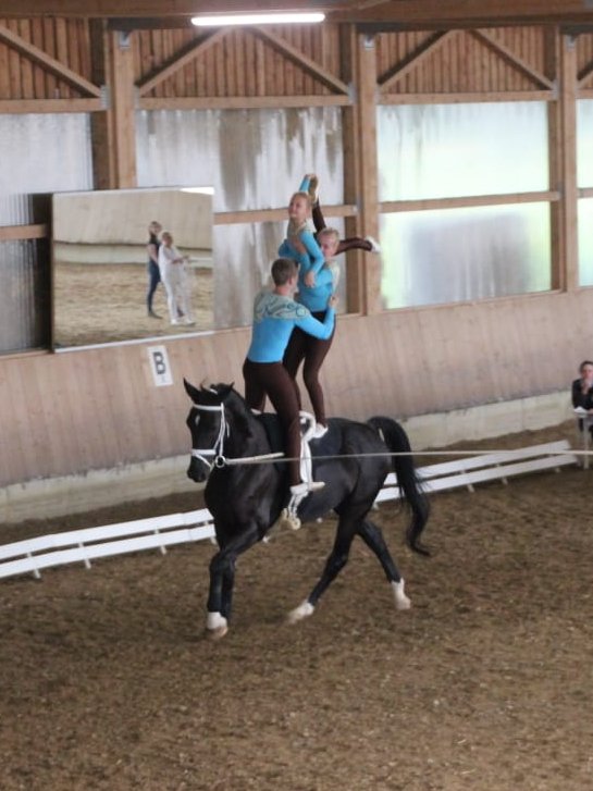 zwei Akrobatinnen währedn der Ausführung akrobatischer Übungen  auf einem reitenden Pferd