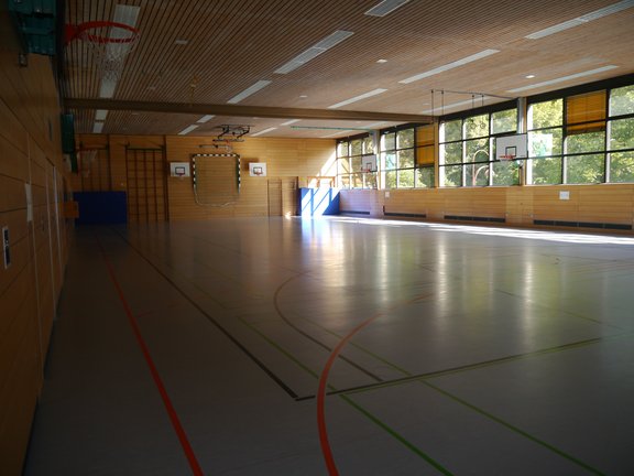 Spielfeld einer Turnhalle mit mehreren Basketballkörben sowie Handballtoren